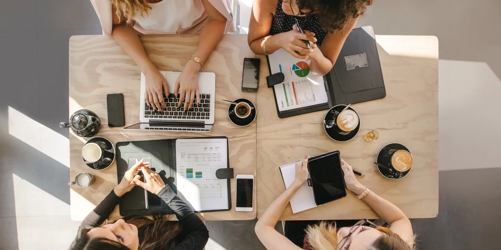 A imagem mostra quatro pessoa reunidas em volta de uma mesa enquanto discutem sobre estratégias de marketing